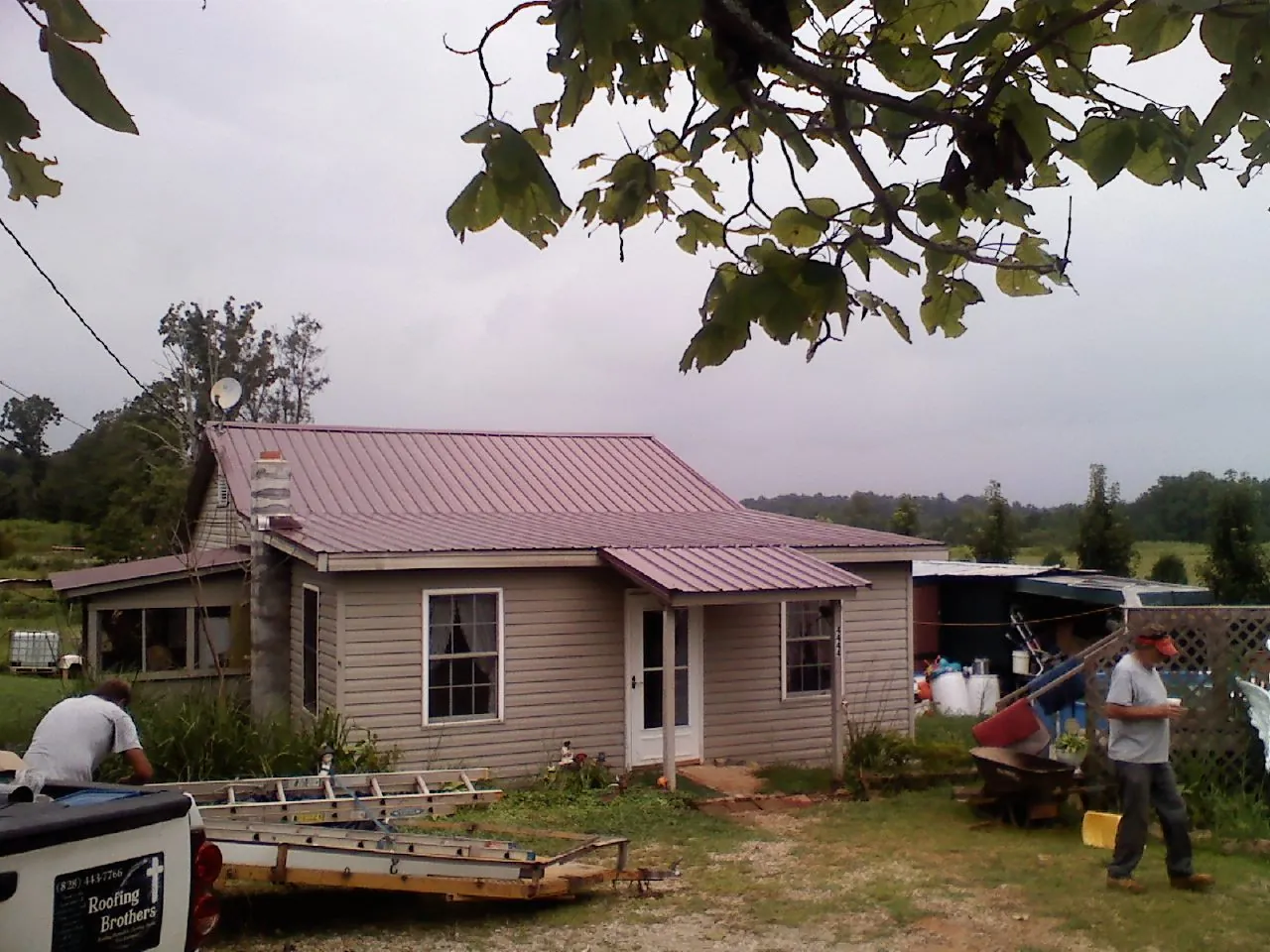 Crew finishing a mauve metal roof on a small farmhouse in White Rock