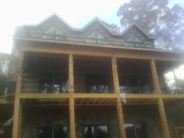 Dormers and porch framing on a large log home under construction — Roof Coating work by our crew in White Rock