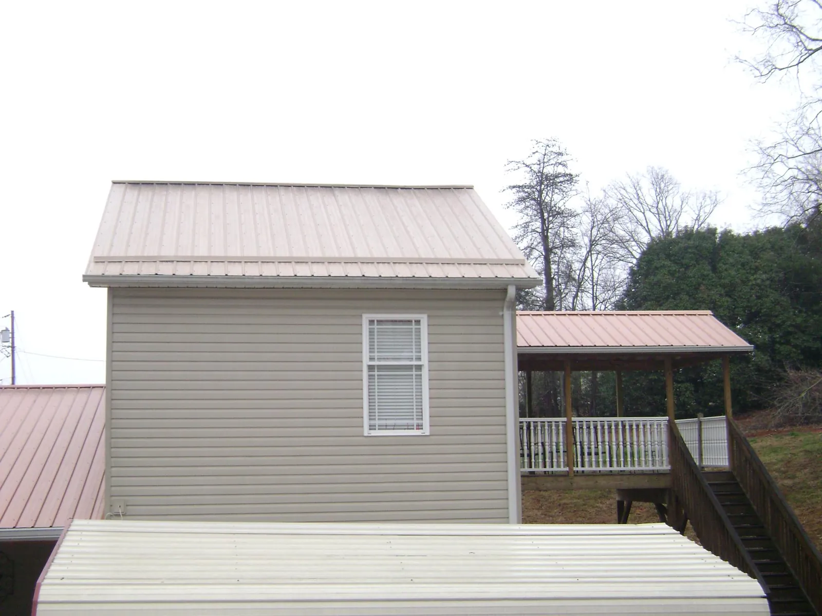 Tan metal roofs on a two story addition and attached porch, from a Roof Replacement job in White Rock