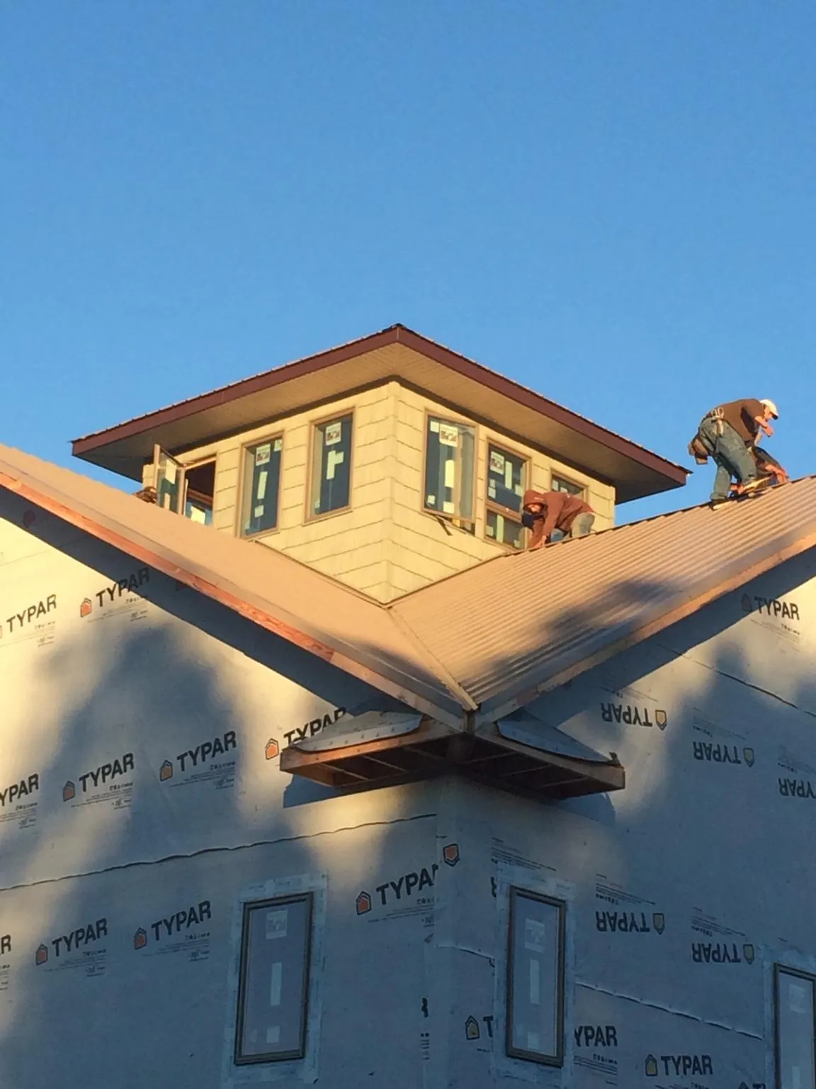 Roofers working around a rooftop cupola on a new metal roof at sunset — Roof Waterproofing in White Rock by Roofing Brothers
